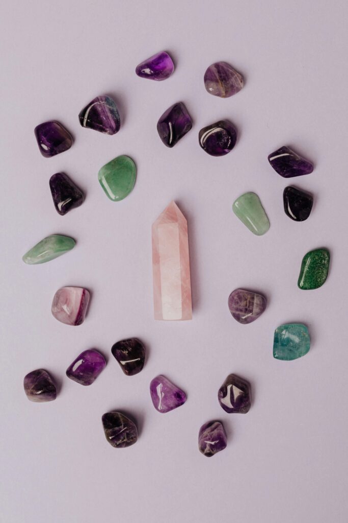 Flat lay of assorted gemstones and rose quartz on a purple background.